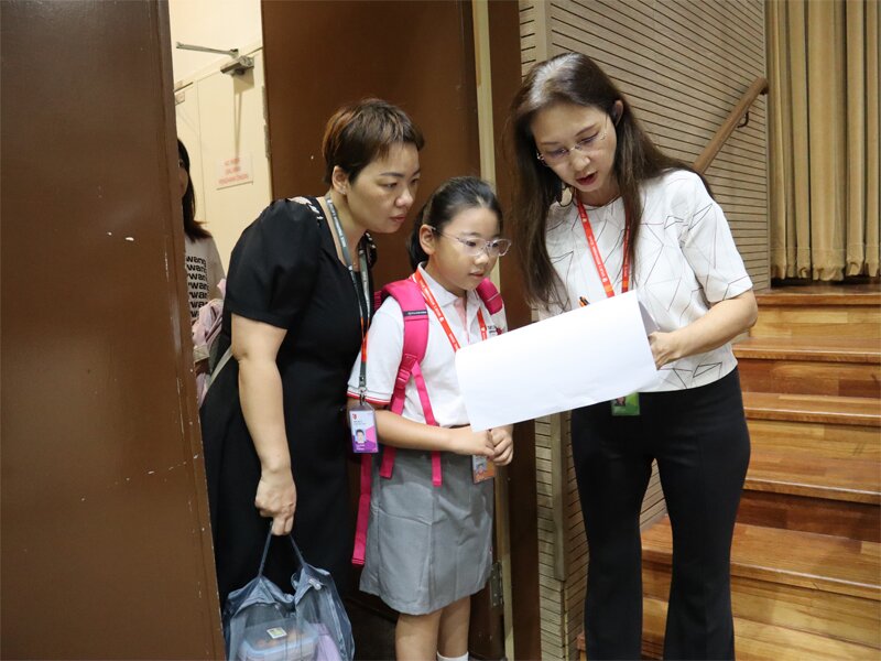 A new student and her parent confirming their information with a school staff.