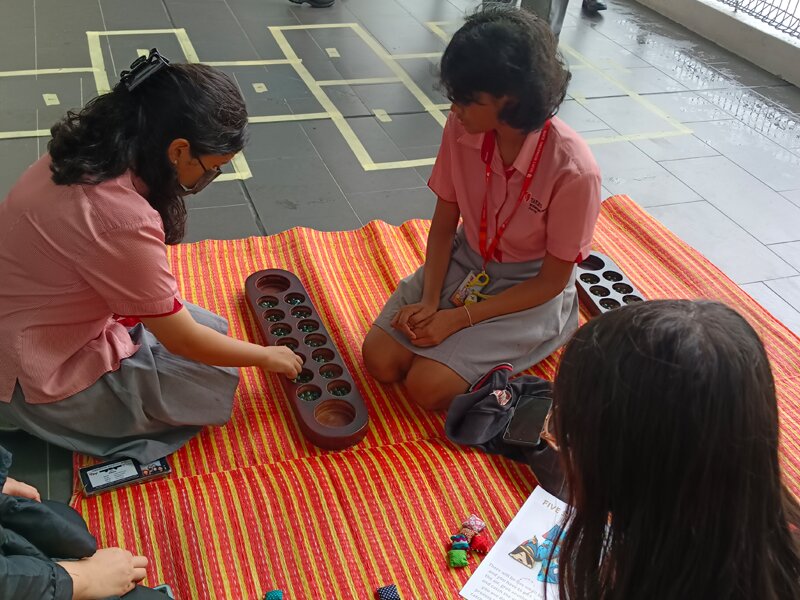 Secondary School students playing with congkak during the Malaysia Month celebration