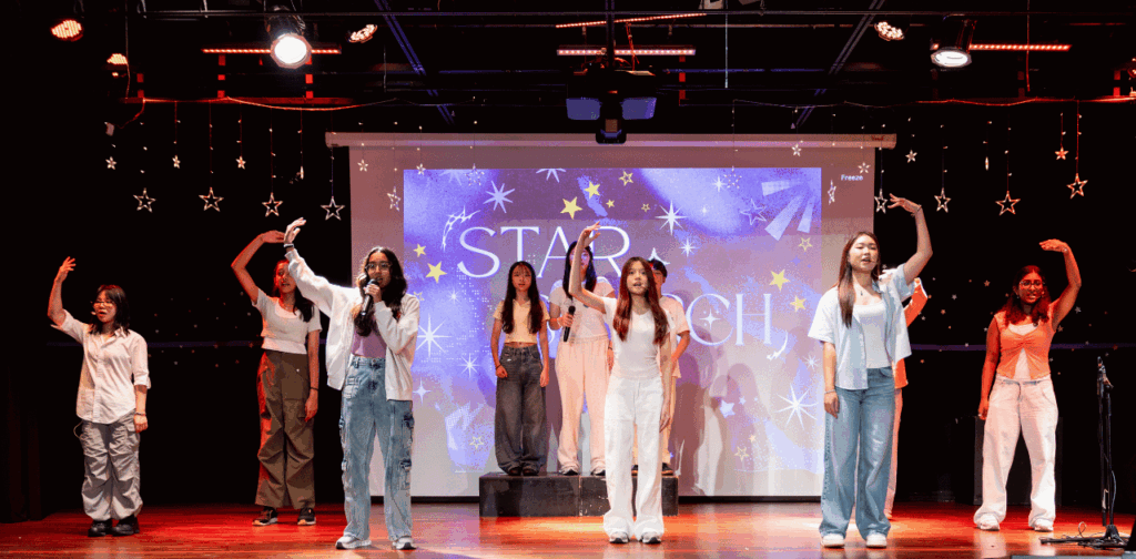 Students singing and performing on stage with a star-themed backdrop during IU Night 2026.