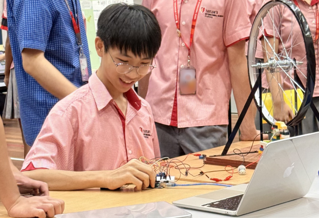 A student demonstrating an electronics prototype that harnesses kinetic energy to generate electricity.