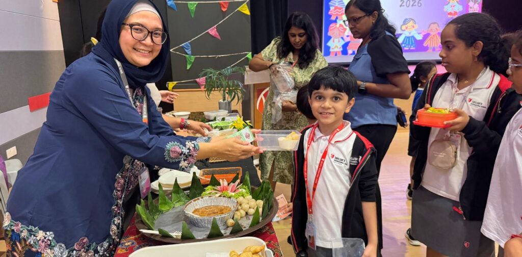 A TISKL student receiving food from a parent volunteer during Flavours of TISKL as part of Diversity Week.