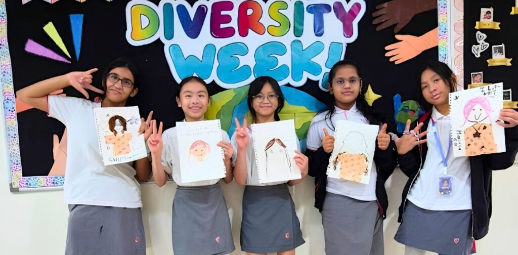 TISKL students holding artwork in front of a Diversity Week student council display.