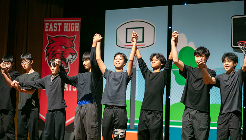 Members of the student backstage crew holding hands and taking a bow on stage during the High School Musical Jr. curtain call.