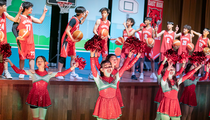 Secondary students performing as East High cheerleaders and basketball players in High School Musical Jr. at Taylor’s International School Puchong.