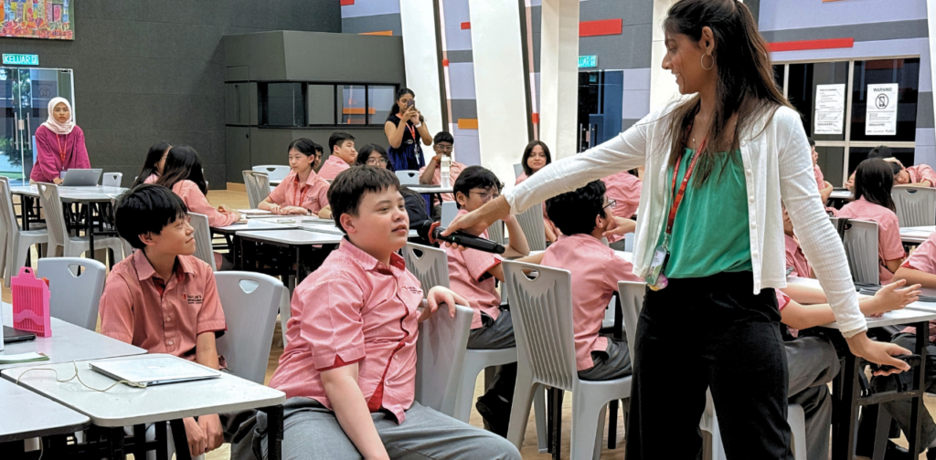 A TISKL staff member holding a microphone for a Year 9 student during an IGCSE exploration session.